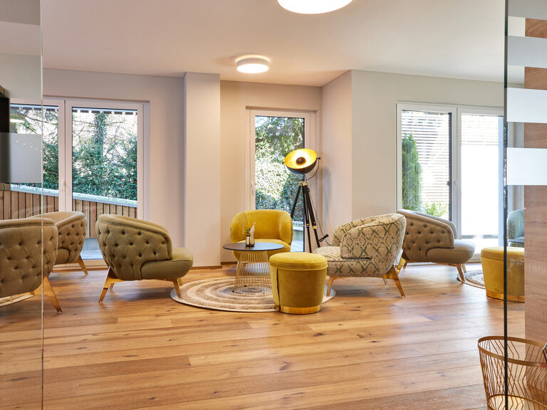 Ein helles, einladendes Wohnzimmer in den Bader Suites mit elegantem Holzboden und gemütlichen Couchmöbeln.