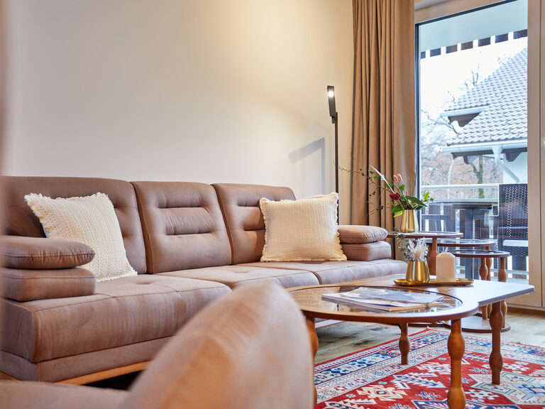 Gemütliche Wohnzimmereinrichtung im Apartment Superior mit weitem Blick aus dem großen Balkonfenster der Bader Suites.