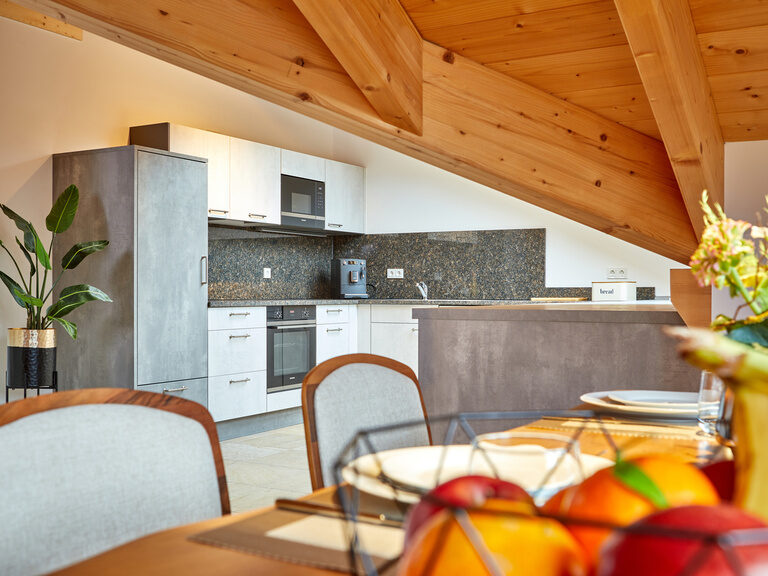 Eine moderne Küche hinter einem frisch gedeckten, stilvollen Holztisch im Apartment der Bader Suites.
