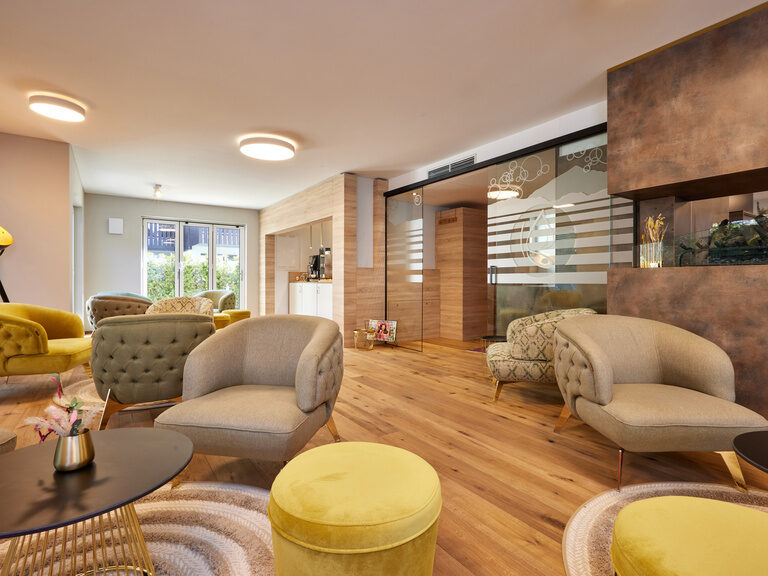 Ein freundliches, lichtdurchflutetes Wohnzimmer in den Bader Suites mit stilvollem Holzboden und komfortablen Polstermöbeln.