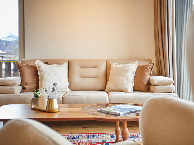 Ein gemütliches Sofa und Sessel im Apartment Superior, ergänzt durch einen eleganten Couchtisch und große, lichtdurchflutende Fenster.